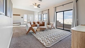 A spacious living room with a large window, a ceiling fan, and a round coffee table. - The Overlook - Hot tub, game room & lake views (Page)