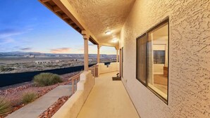 A covered outdoor area with a view of a desert landscape, a pathway, and a building with large windows. - The Overlook - Hot tub, game room & lake views (Page)