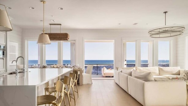 A modern kitchen with a large island, bar stools, and a view of the ocean.