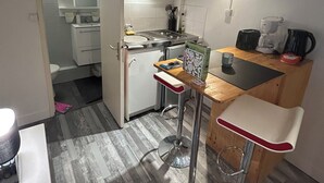 A compact kitchen with a small dining area, including a bar stool and a coffee machine. - Cosy Studio Rouen Hôtel de Ville (Rouen)