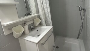 A bathroom with a white sink, mirror, and shower. - Cosy Studio Rouen Hôtel de Ville (Rouen)