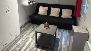 A compact living space with a sofa, a small table, and a cabinet. - Cosy Studio Rouen Hôtel de Ville (Rouen)