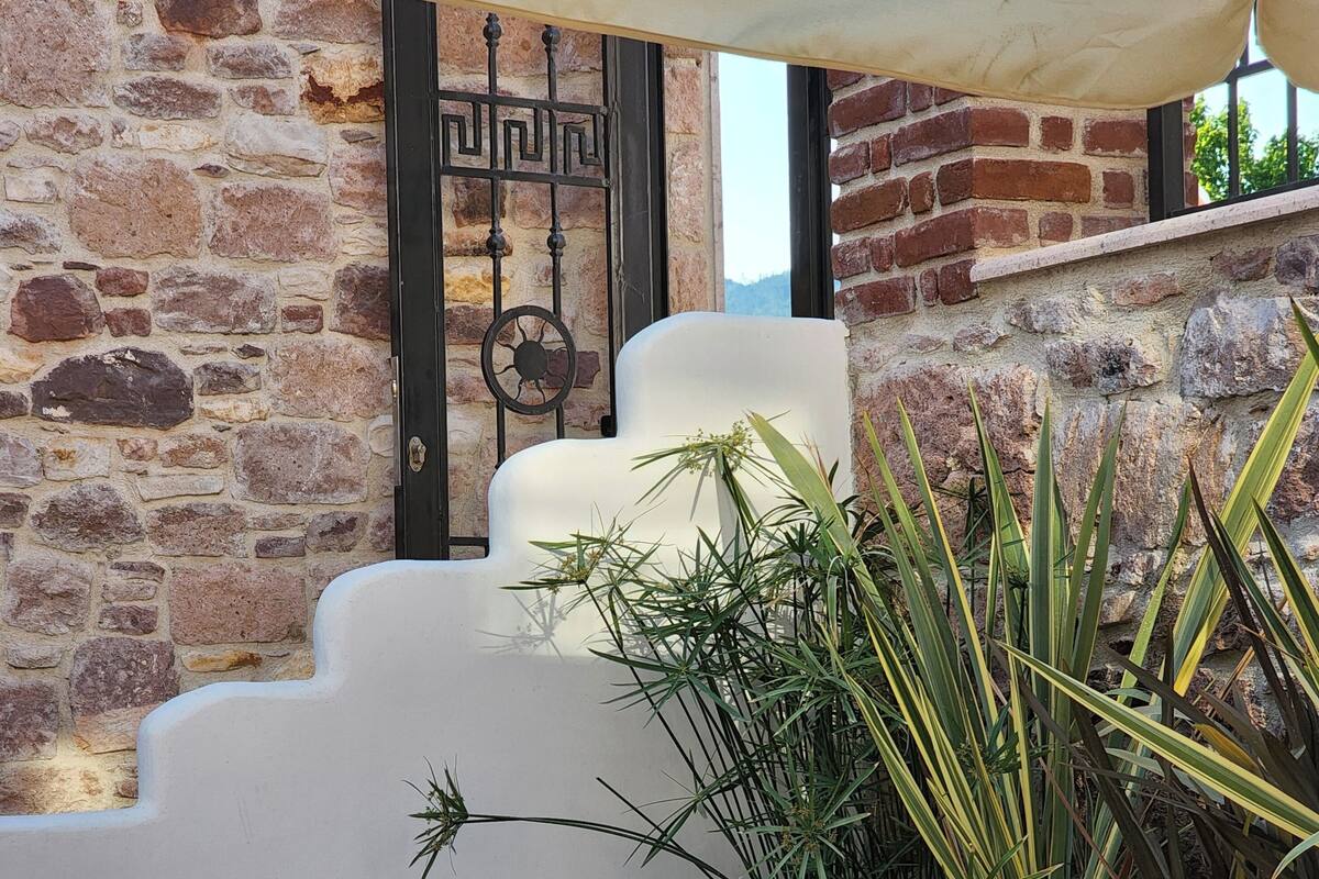 A cozy outdoor seating area with a wooden table, cushions, and a bowl of fruit.