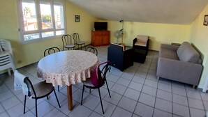 Una sala de estar con una mesa redonda, sillas, un sofá y una televisión.