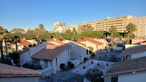 Zona residencial con varios edificios, algunos con techos de tejas rojas y algunos con balcones. Hay árboles y un cielo despejado.