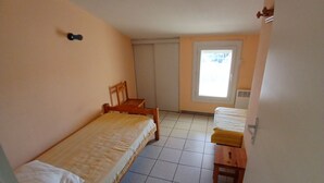 Una habitación pequeña con cama individual, una silla y una mesita.