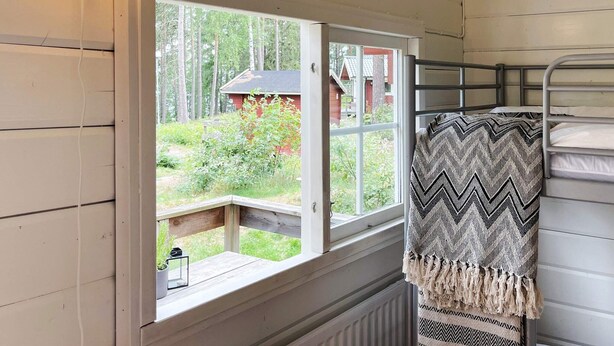 A cabin room with a window overlooking a garden, a bunk bed, and a hanging light fixture. - 3 Person Holiday Park Home in Vaxholm (Vaxholm)