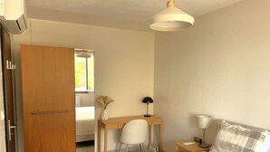 A bedroom with a bed, a desk, a chair, a lamp, and a wardrobe.