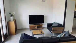 A modern living room with a flat-screen TV, a sofa, a coffee table, and a side table. - Villa with panoramic lake view close to the beach (Conjux)