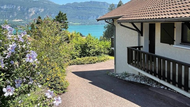 A house with a tiled roof, a balcony, and a view of a lake and mountains. - Villa with panoramic lake view close to the beach (Conjux)