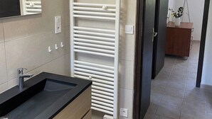 A modern bathroom with a black sink, a mirror, a white towel rack, and a wooden cabinet. - Villa with panoramic lake view close to the beach (Conjux)