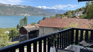 A terrace with a table and chairs, overlooking a lake and mountains.