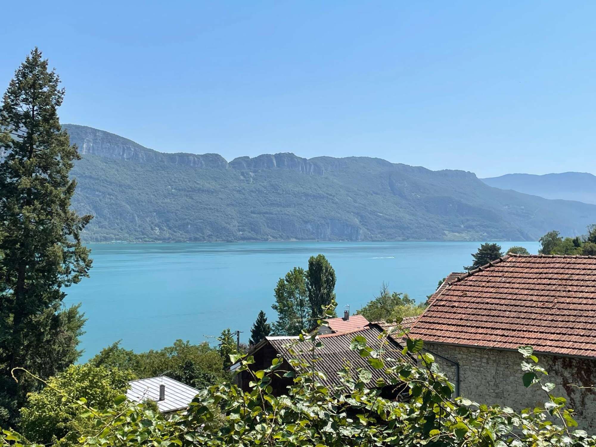 A mountainous landscape with a lake and a building with a red roof.
