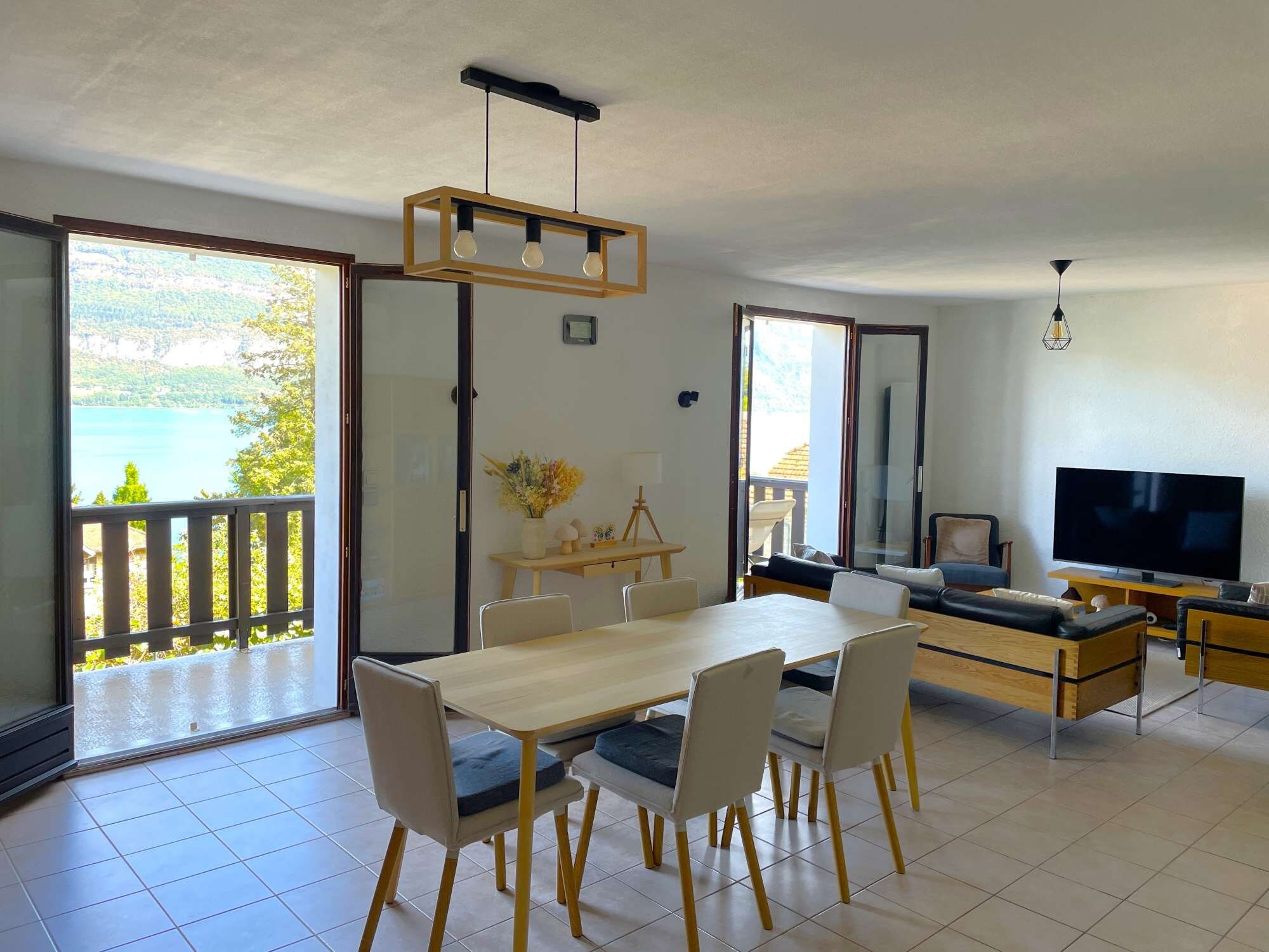 Un salón moderno con comedor, televisor y balcón con vista al mar.
