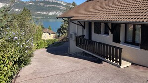 A house with a tiled roof, a balcony, and a view of a lake and mountains.
