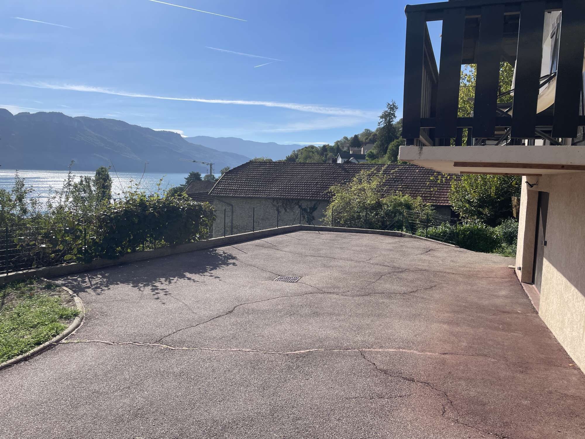 Une allée pavée mène à un bâtiment d’où l’on a vue sur un lac et des montagnes.