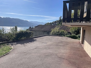 A paved driveway leading to a building with a view of a lake and mountains. - Villa des Lardars · Villa 4* · Panoramic lake view & close to the beach (Conjux)