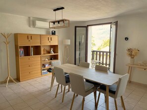 A dining area with a table, chairs, a cabinet, and a view through a glass door. - Villa des Lardars · Villa 4* · Panoramic lake view & close to the beach (Conjux)