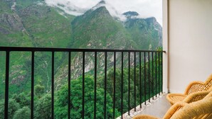Un balcon offrant une vue sur des montagnes verdoyantes et des nuages.