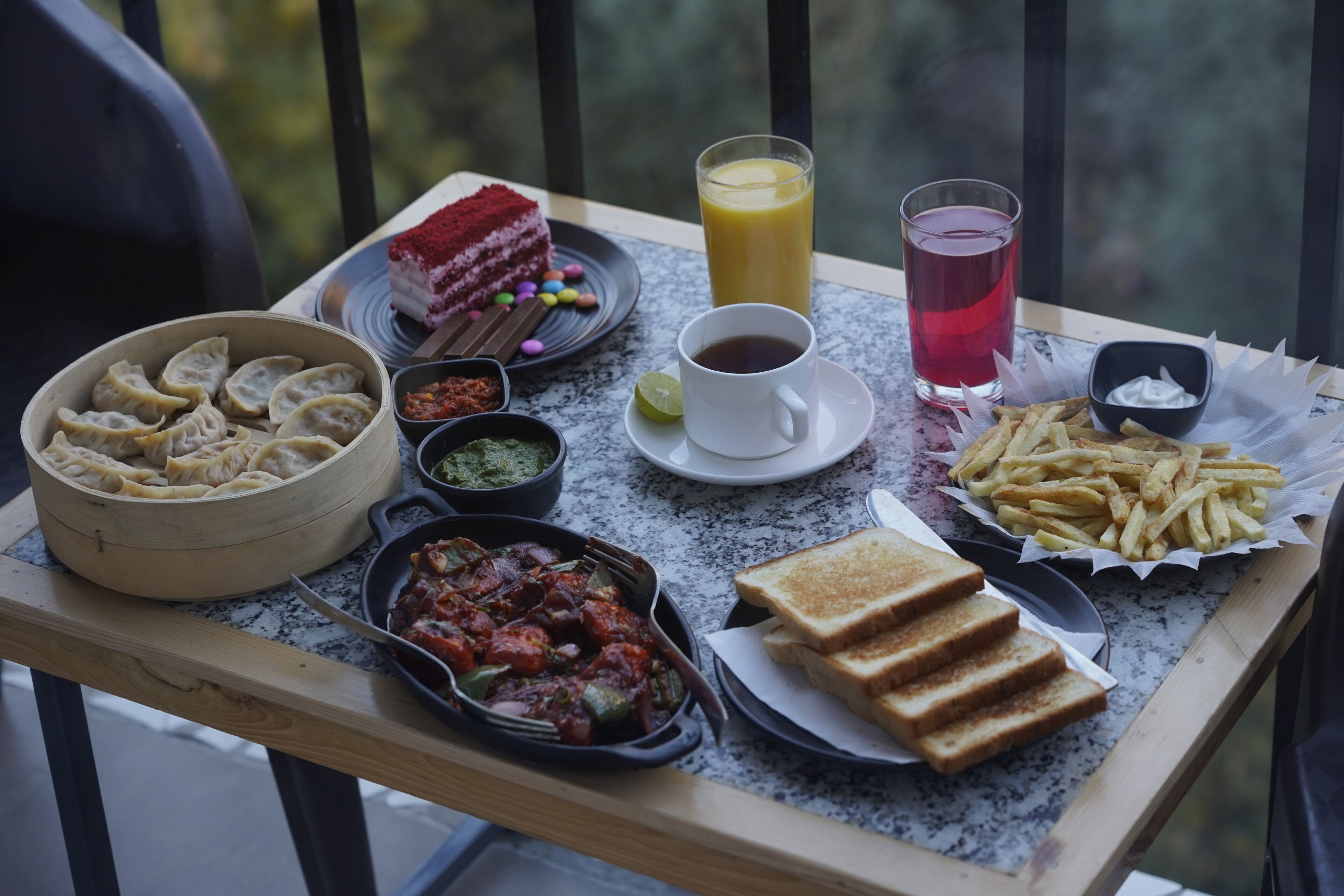 A tray with food items including dumplings, a red velvet cake, French fries, toast, and a cup of coffee.