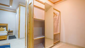 A hotel room with a wooden bed, a bedside table, a wardrobe, and a bathroom.