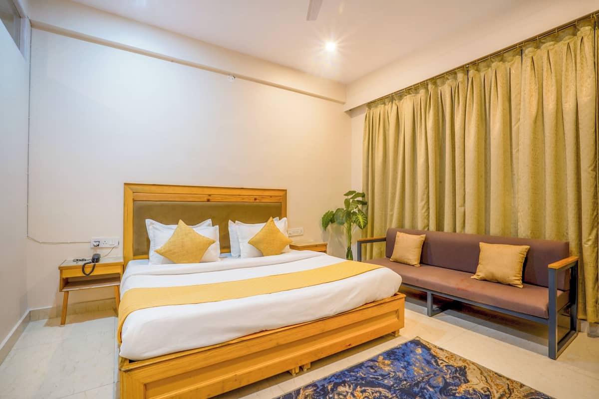 A bedroom with a wooden bed, a sofa, and a large window with curtains.