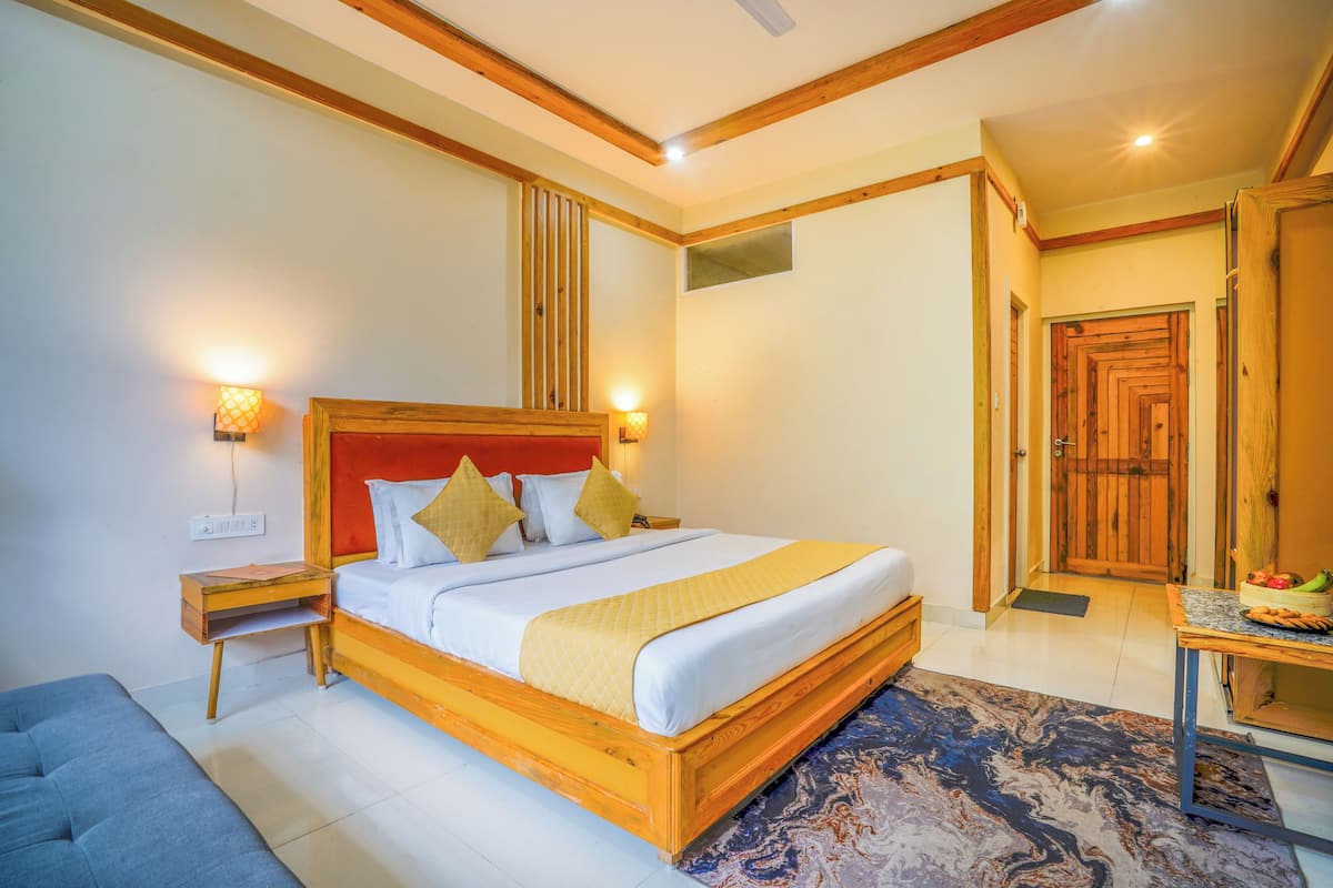 A bedroom with a wooden bed, bedside tables, a bench, and a small table with fruits.