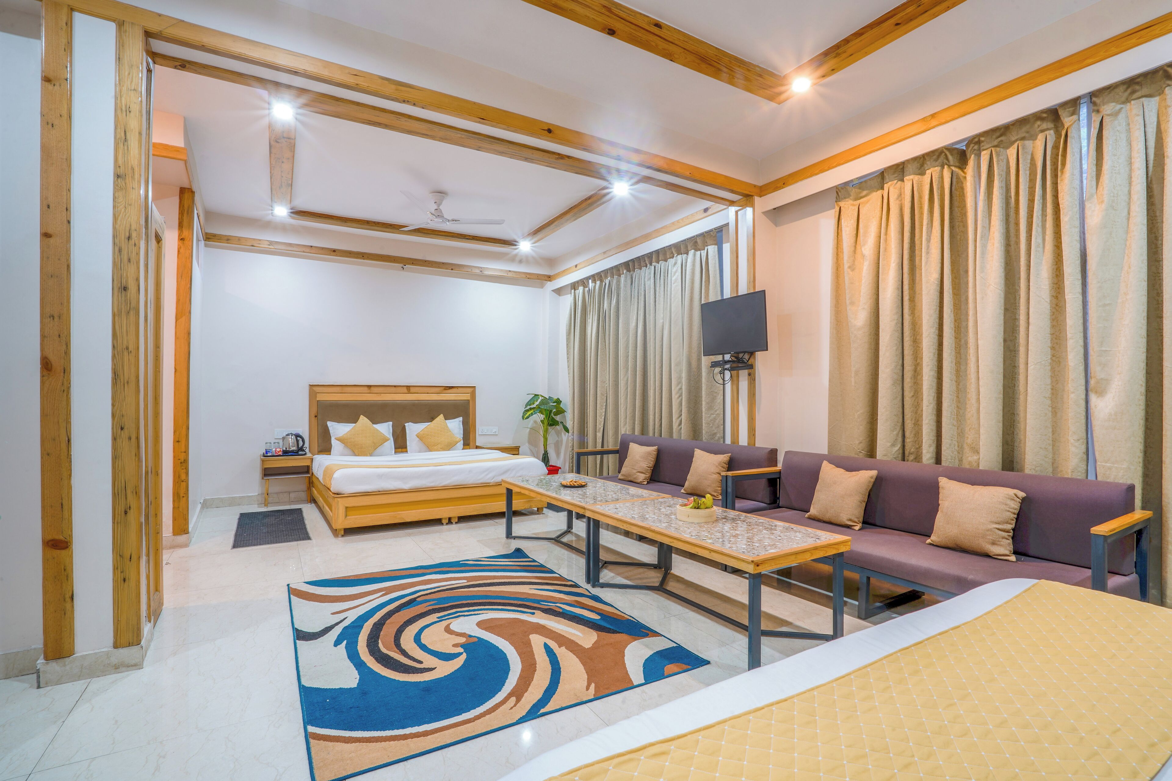 Une chambre d’hôtel avec un lit, un canapé, une télévision et une table à manger.
