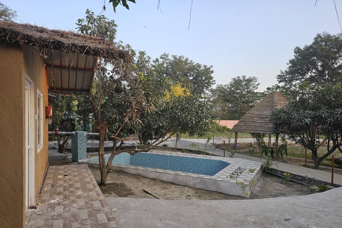 A residential area with a swimming pool, a thatched-roof structure, and a tiled patio.