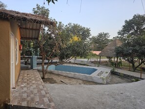 Un quartier résidentiel doté d’une piscine, d’une construction à toit de chaume et d’un patio carrelé.