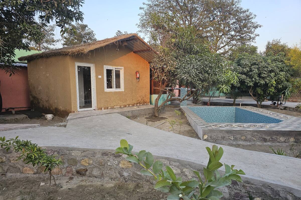 A small house with a thatched roof, a tiled pool, and a garden area.
