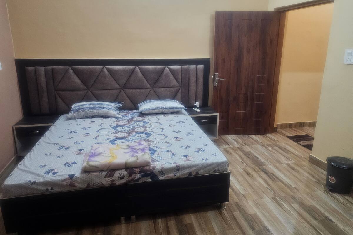 A neatly made bed with a patterned bedspread, a headboard, and two bedside tables with lamps.