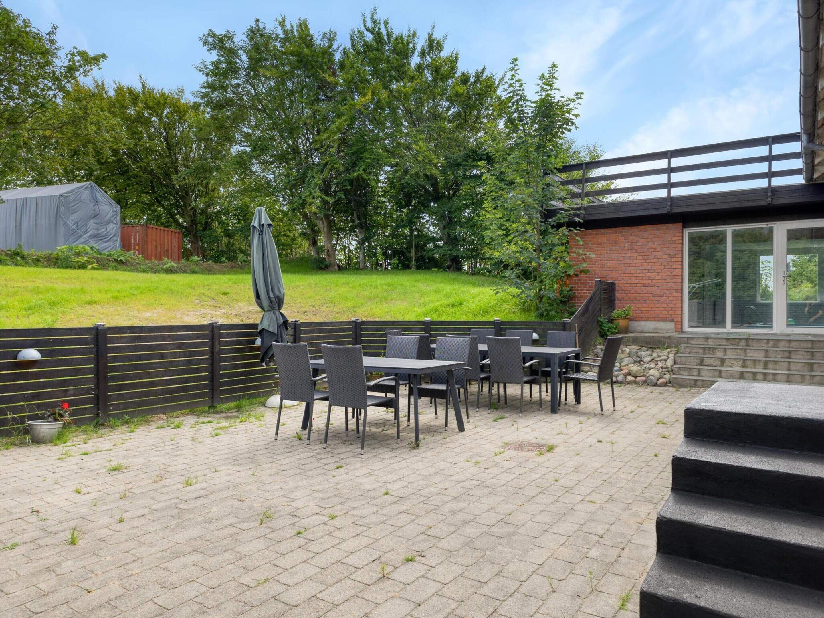 An outdoor patio area with tables and chairs, a covered seating area, and a brick building in the background.