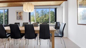A modern dining area with a wooden ceiling, large windows, and a view of trees. - 5 Star Holiday Home in Lokken (Hirtshals)