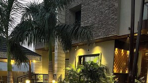 A courtyard with a stone wall, palm trees, and potted plants.