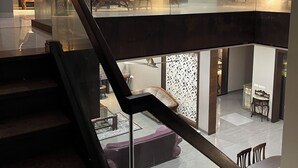 Un interior moderno con una escalera de vidrio que conduce a una sala de estar en un segundo piso.
