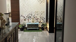 A modern hallway with a decorative wall, a bench with a Buddha statue, and potted plants.