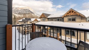 Un balcón cubierto de nieve con vistas a una montaña y un edificio de estilo chalet.