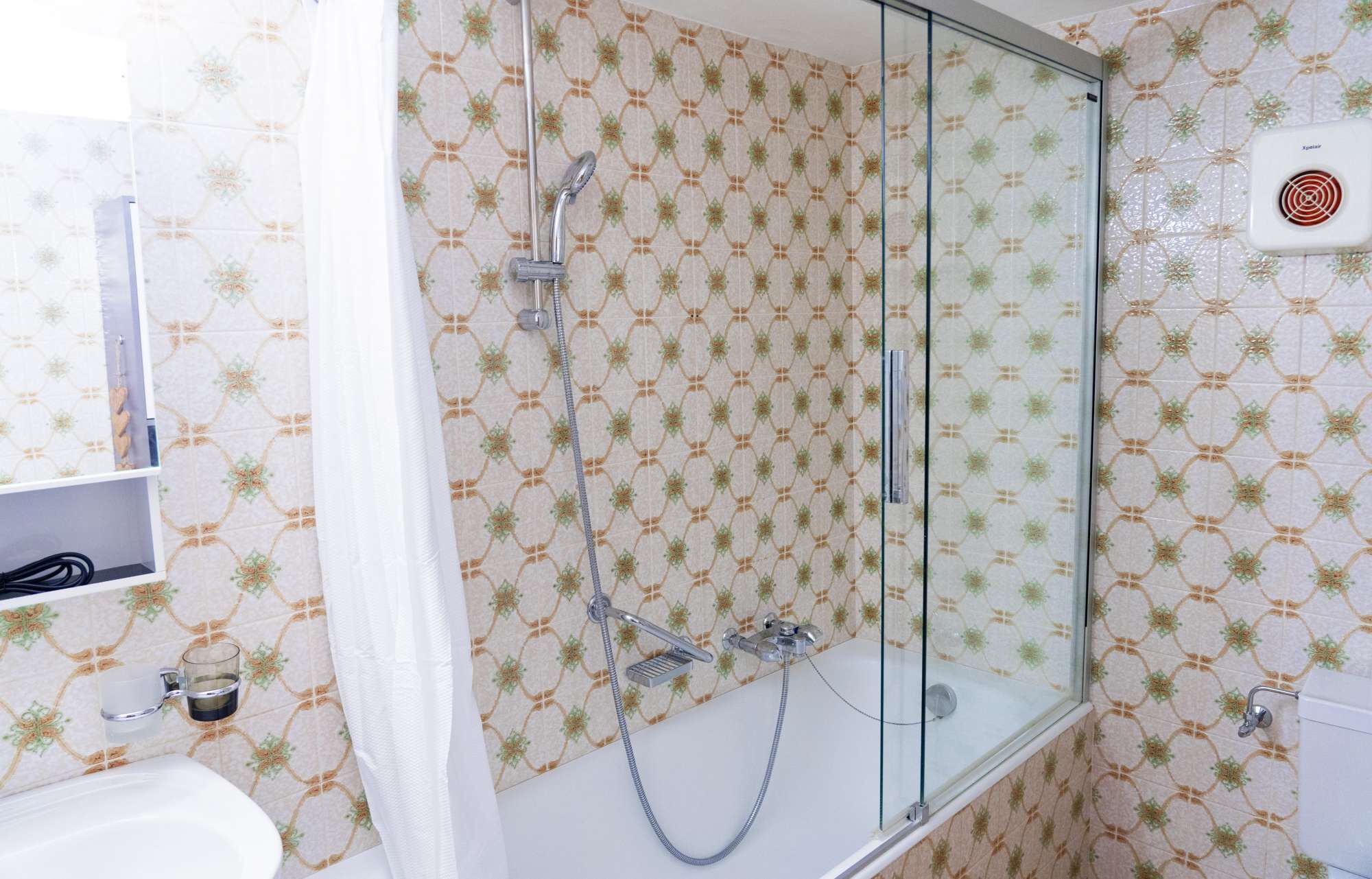 Ein Badezimmer mit einer Duschkabine, einem weißen Waschbecken und einer Toilette.