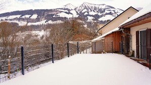 A snow-covered landscape with a mountain in the background and a building with a sloped roof.