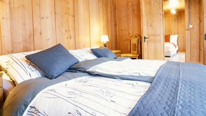 A wooden room with a bed, two bedside tables, and a nightstand.