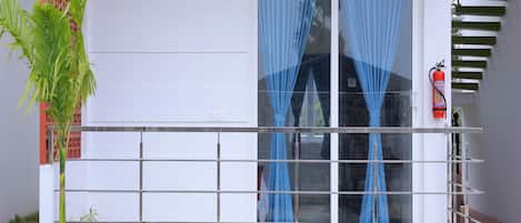 A modern building with a white exterior, a glass door with blue curtains, and a metal staircase.