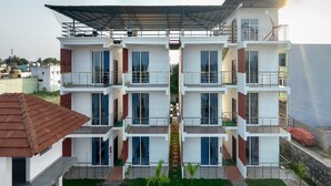 A multi-story hotel with a covered entrance, a central staircase, and a landscaped courtyard. - Anglo Resort (Puducherry)