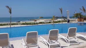 A poolside area with lounge chairs and a view of the beach and ocean. - Stunning 2BR Apartament With Pool in Santa Marta (Santa Marta)