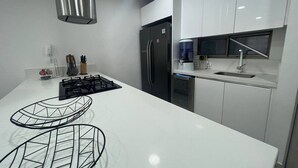 A modern kitchen with white cabinetry, a stainless steel refrigerator, a built-in dishwasher, and a gas stove. - Stunning 2BR Apartament With Pool in Santa Marta (Santa Marta)