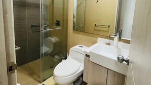 A modern bathroom with a glass-enclosed shower, a toilet, and a sink with a mirror above it. - Stunning 2BR Apartament With Pool in Santa Marta (Santa Marta)