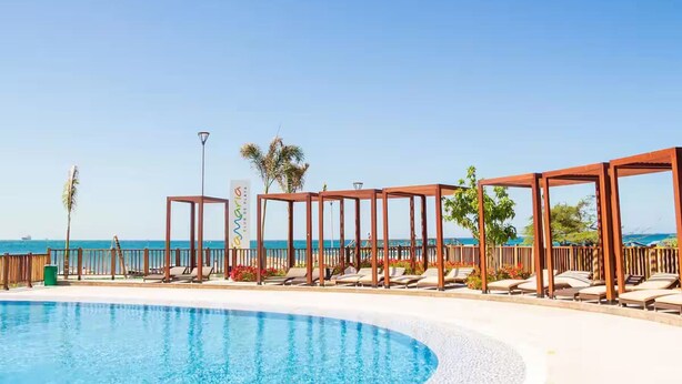 A poolside area with lounge chairs and wooden pergolas, overlooking a clear blue sea. - Stunning 2BR Apartament With Pool in Santa Marta (Santa Marta)