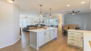 A spacious kitchen with a central island, pendant lighting, and a dining area with a table and chairs.