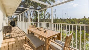 A wooden deck with a table and chairs, a bench, and a grill.