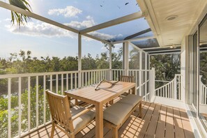 A wooden deck with a table and chairs, overlooking a lush green landscape.